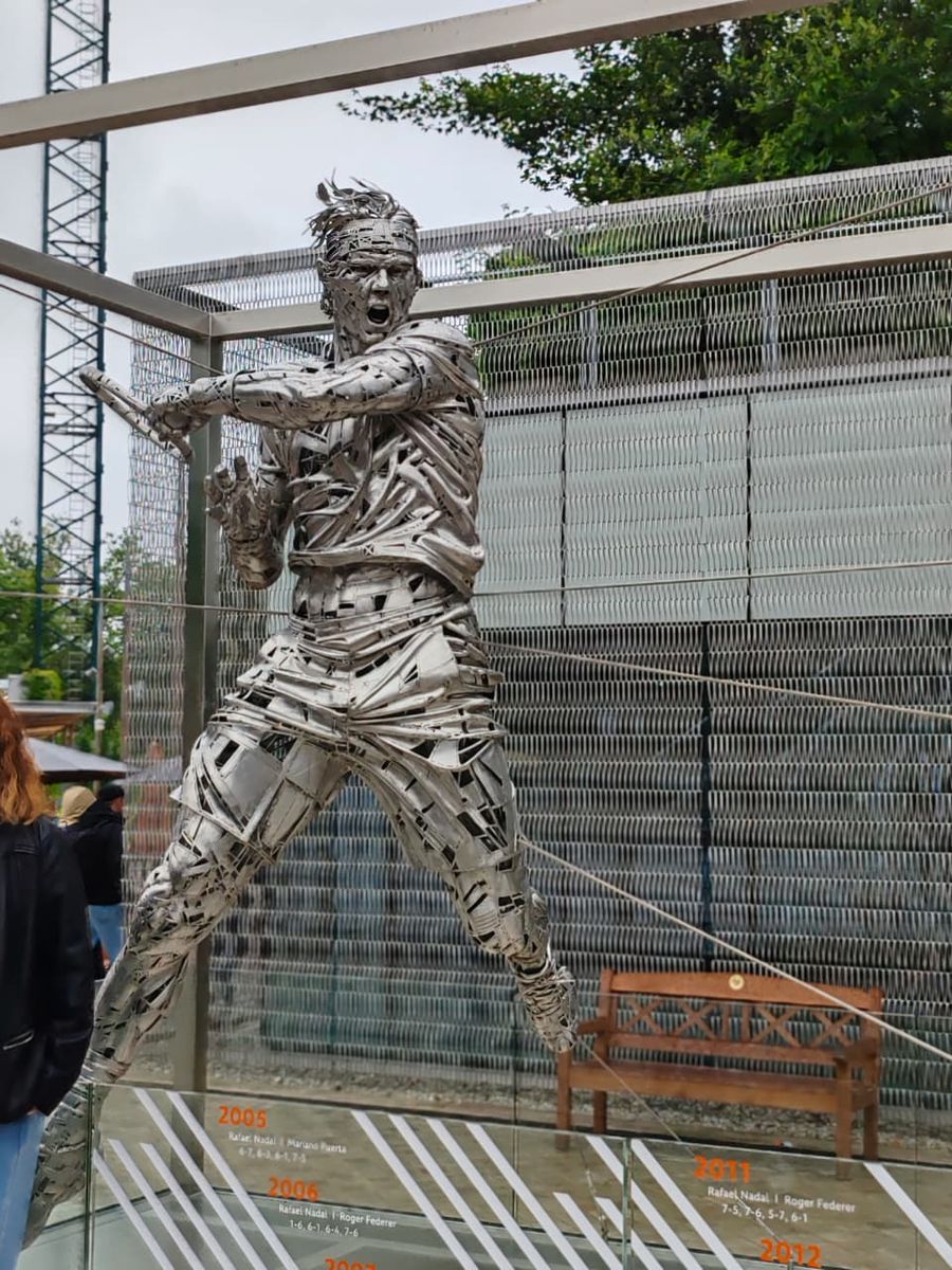 Escultura metálica de un tenista en los jardines del complejo