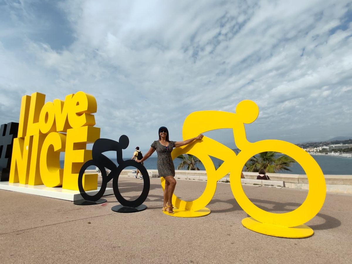 Mujer del grupo junto a la escultura de ciclistas en Niza