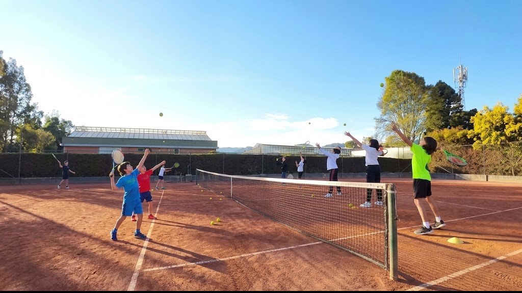 Jóvenes entrenando saque y volea a lado y lado de la red