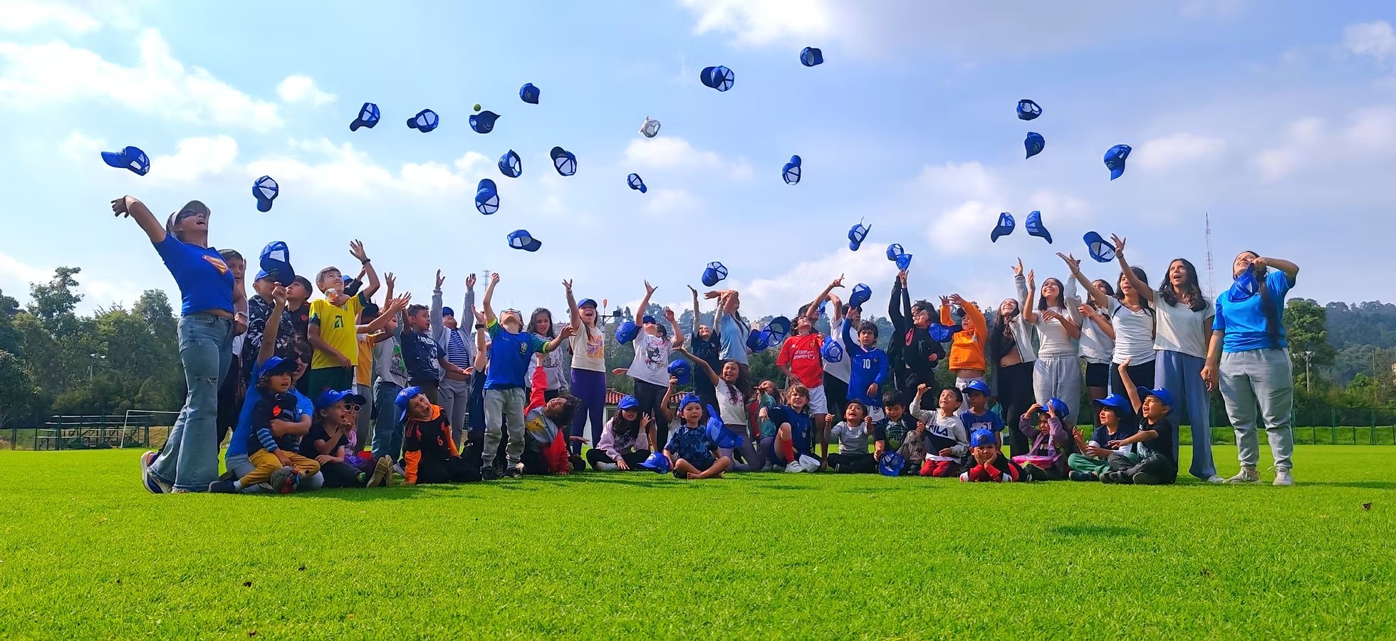 Grupo del curso vacacional lanzando las cachuchas al aire en la cancha de Bogotá